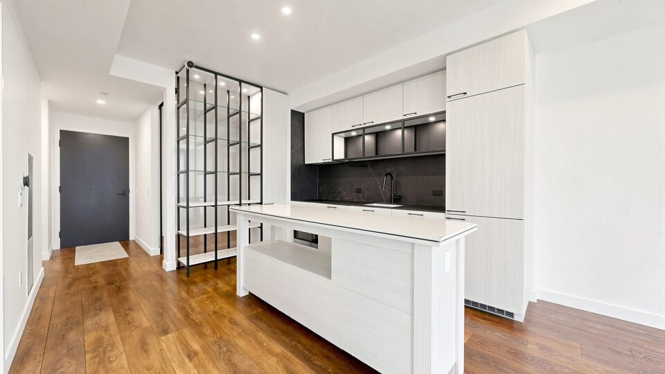 Kitchen island with stone counter, full-height cabinetry and a glass-and-steel pantry screen