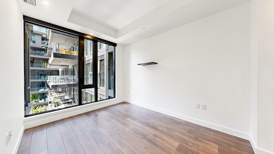 Primary bedroom with a corner window and wide plank flooring